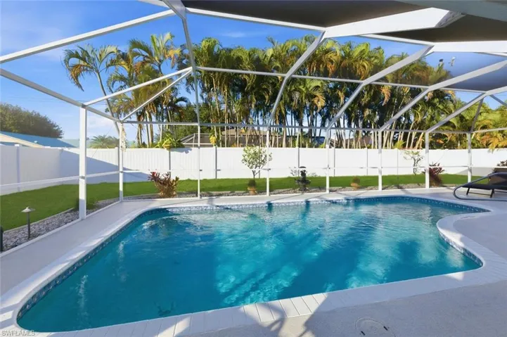 View of swimming pool with a sunroom, glass enclosure, and a fenced backyard