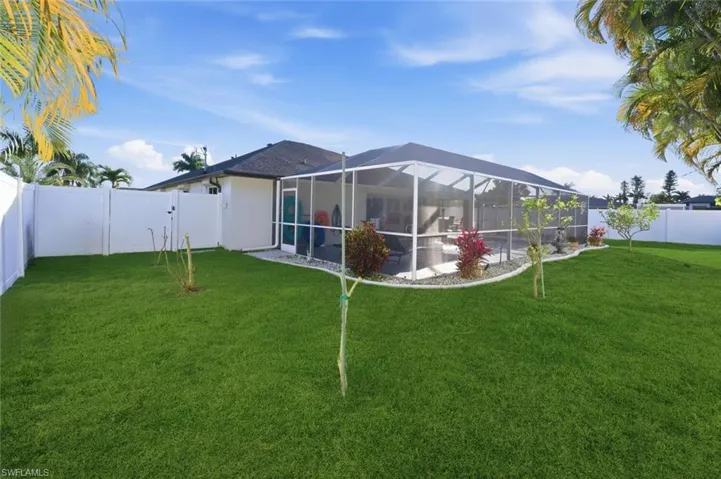 Back of property with a fenced backyard, a lanai, a sunroom, and a gate
