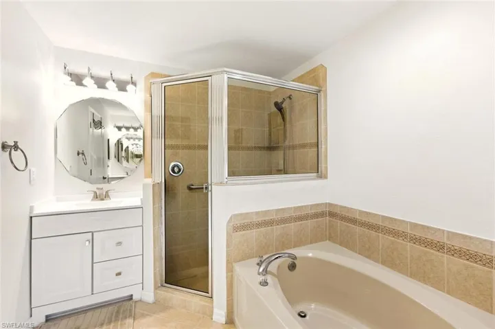 Bathroom featuring vanity, a garden tub, a shower stall, and light tile patterned floors