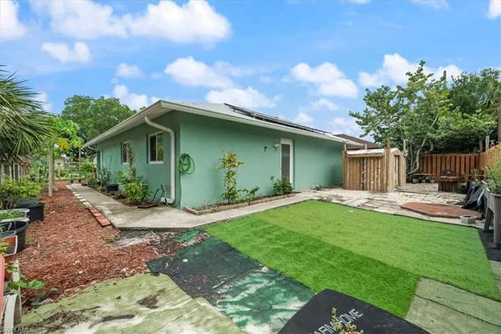 Back of house featuring a fenced backyard, solar panels, stucco siding, and a patio
