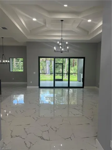 Unfurnished room with tile patterned floors, a healthy amount of sunlight, and a chandelier