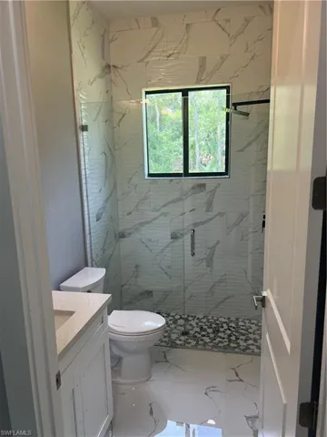 Bathroom with tile patterned flooring, a shower with door, toilet, and vanity