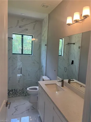 Bathroom with vanity, tile patterned floors, a shower with shower door, and toilet