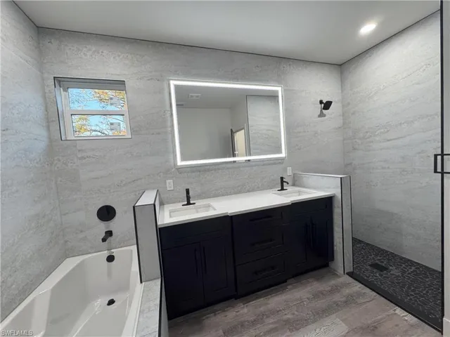 Bathroom with hardwood / wood-style floors, vanity, and tile walls