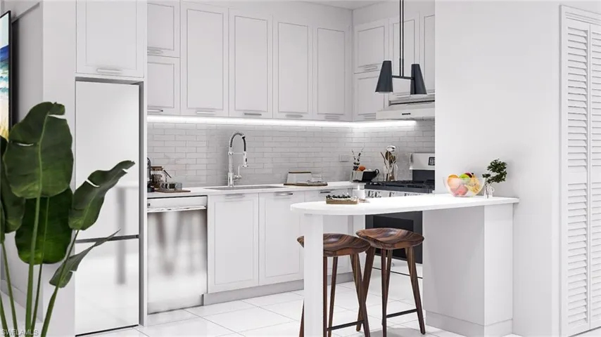 Kitchen with a kitchen bar, white cabinets, tasteful backsplash, and appliances with stainless steel finishes