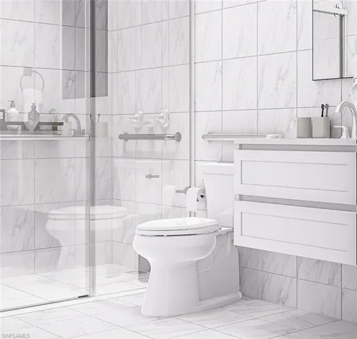 Bathroom with tile walls, vanity, a shower stall, and light marble finish floors