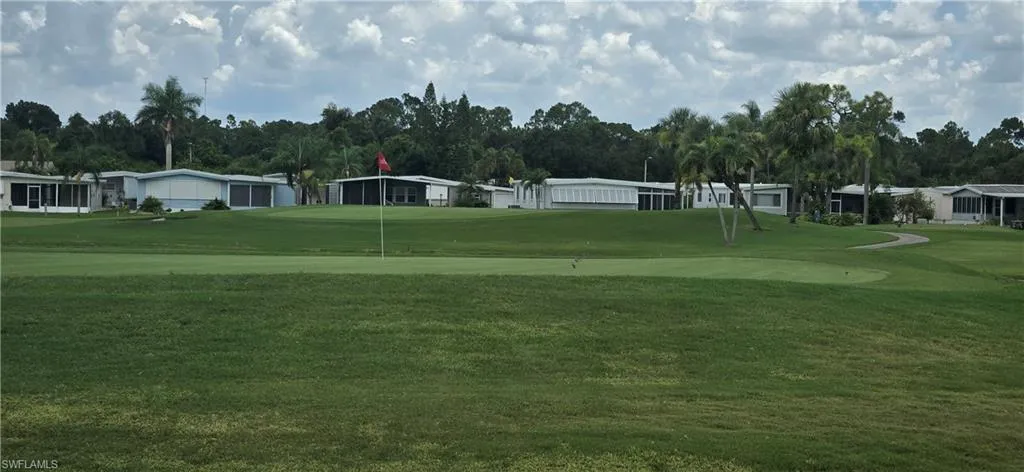 View of property's community with golf course view, a lawn, and a putting green