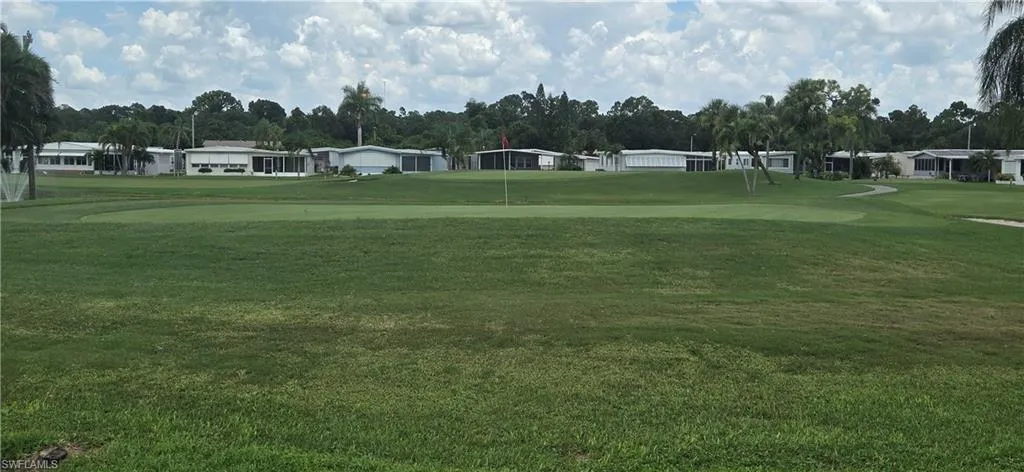 View of property's community with view of golf course, a lawn, and a residential view