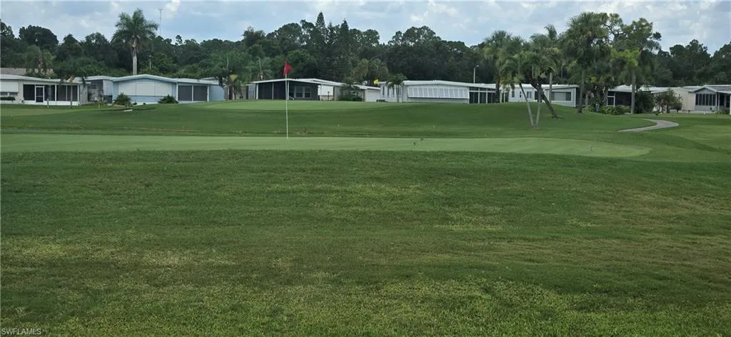 View of community featuring golf course view, a lawn, a residential view, and a putting area