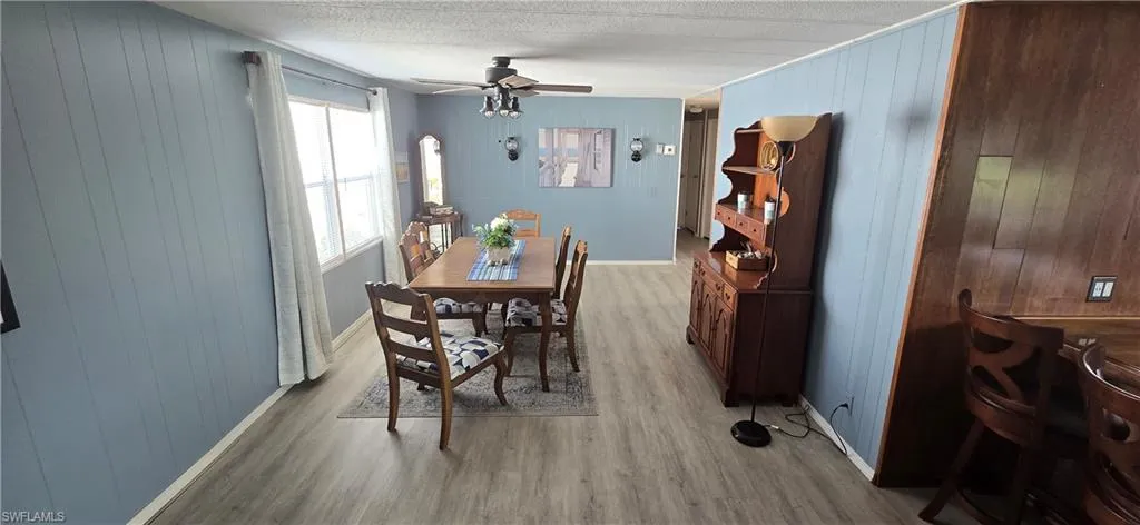 Dining area featuring light wood-style floors, ceiling fan, and wood walls