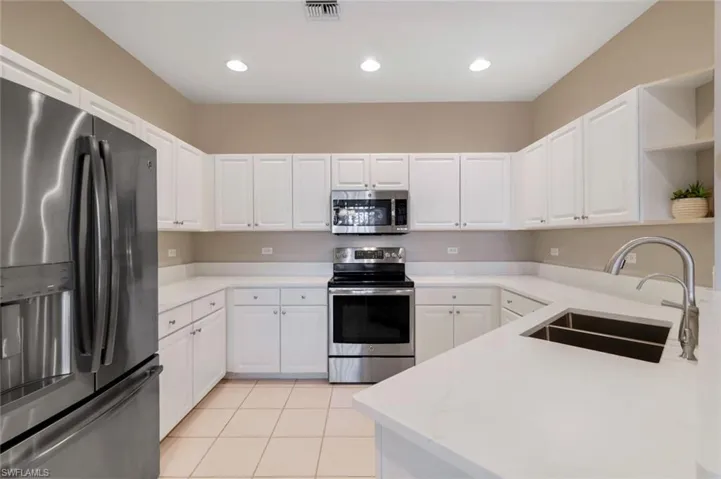 Kitchen featuring appliances with stainless steel finishes, recessed lighting, white cabinets, light tile patterned flooring, and open shelves