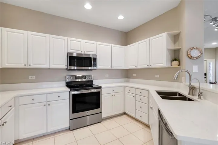 Kitchen with appliances with stainless steel finishes, open shelves, a peninsula, recessed lighting, and white cabinets