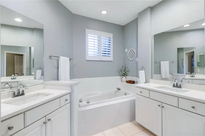 Bathroom with two vanities, a garden tub, tile patterned flooring, and recessed lighting