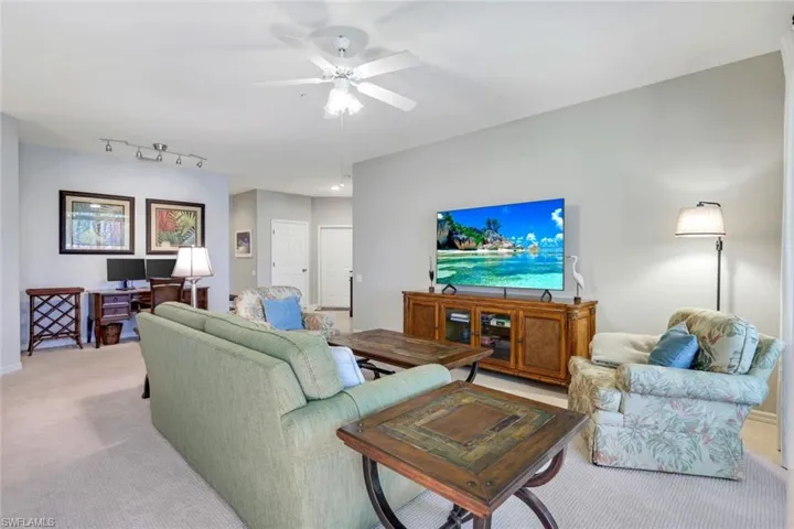 Living room featuring a desk, light colored carpet, and a ceiling fan