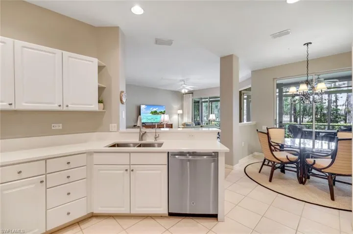 Kitchen with stainless steel dishwasher, a peninsula, recessed lighting, light tile patterned flooring, and white cabinets