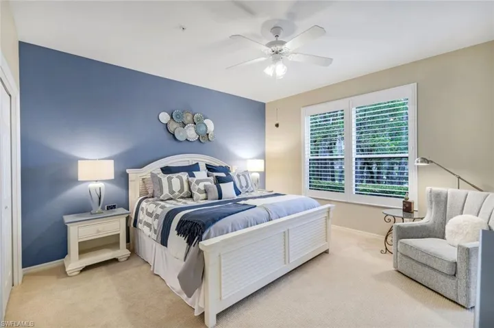 Bedroom with light colored carpet and a ceiling fan