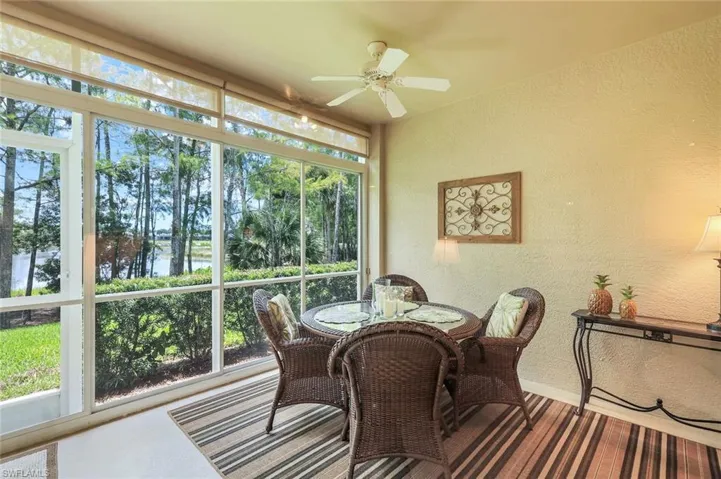 Sunroom with a textured wall, a ceiling fan, outdoor dining space, and a water view