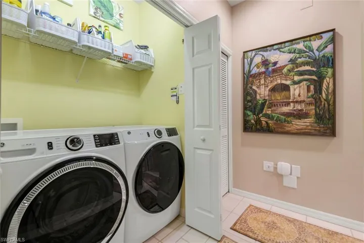 Laundry room featuring washer and clothes dryer and light tile patterned flooring