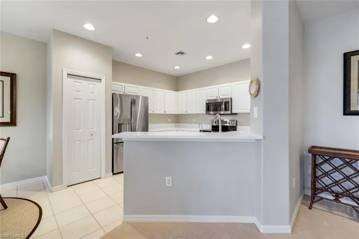 Kitchen featuring white cabinetry, stainless steel appliances, light countertops, a peninsula, and light tile patterned flooring