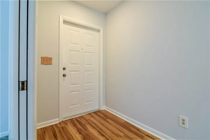 Interior Foyer With Beautiful Warm Laminate Flooring And Pocketing Doors Into Living Room.