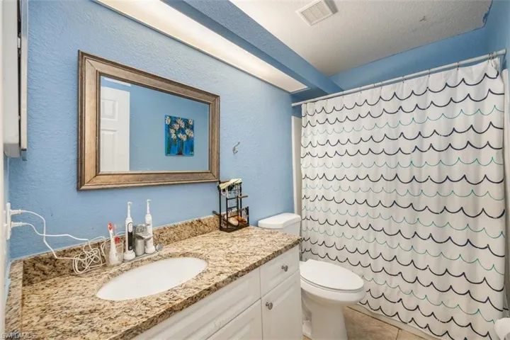 Full bath featuring a textured wall, vanity, a textured ceiling, and light tile patterned flooring