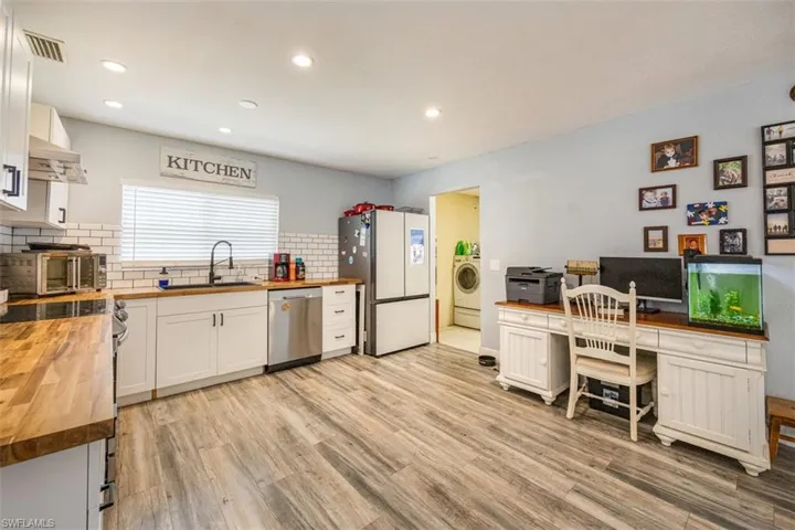 Kitchen with wood counters, white cabinetry, stainless steel appliances, tasteful backsplash, and light wood-type flooring
