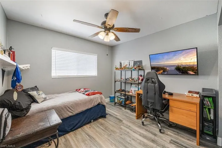 Bedroom featuring wood finished floors, an office area, and a ceiling fan