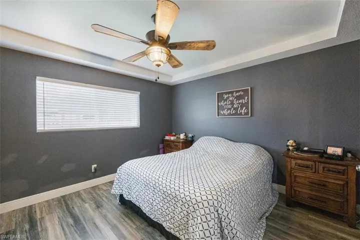 Bedroom featuring a tray ceiling, wood finished floors, and a ceiling fan