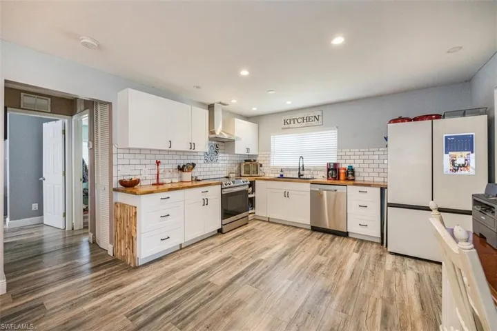 Kitchen featuring wooden counters, white cabinets, appliances with stainless steel finishes, and recessed lighting