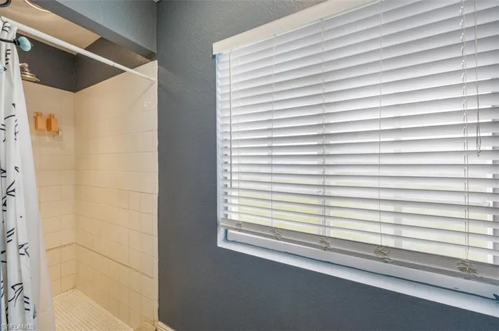 Full bath featuring a textured wall and a shower stall