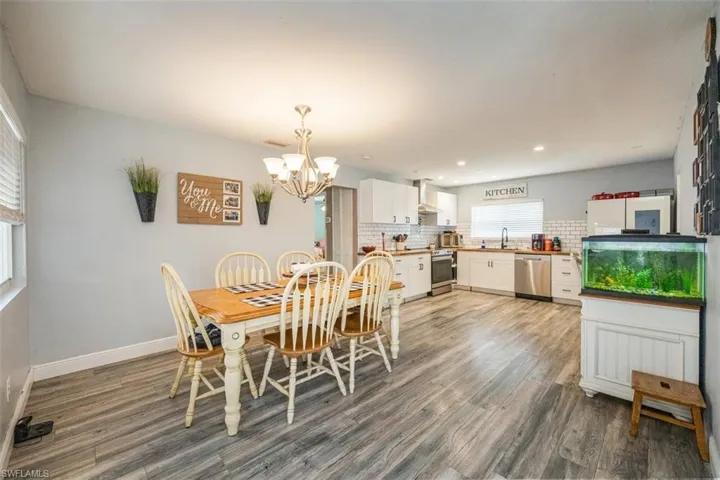 Dining room with dark wood-type flooring, a chandelier, and recessed lighting
