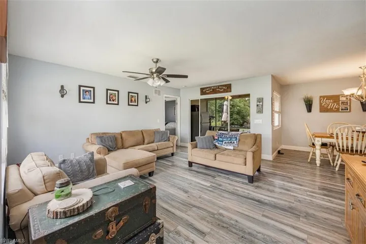 Living area with light wood-style floors, a ceiling fan, and a chandelier
