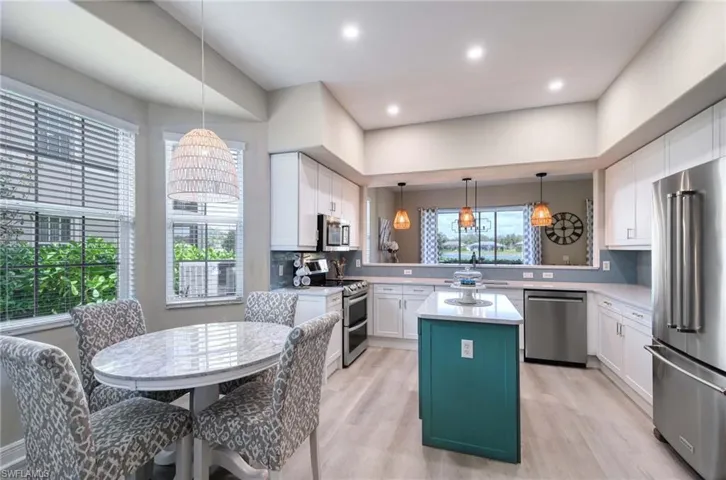 Kitchen featuring stainless steel appliances, white cabinetry, backsplash, a center island, and light wood-type flooring