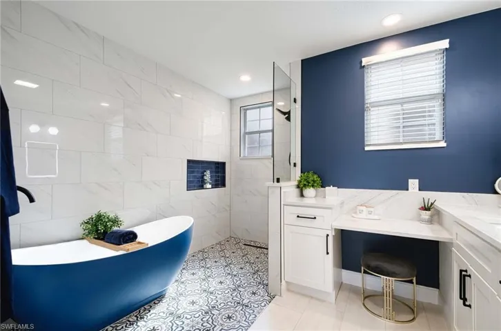 NEW PRIMARY BATH with vanity, independent shower and bath, tile patterned floors, and tile walls