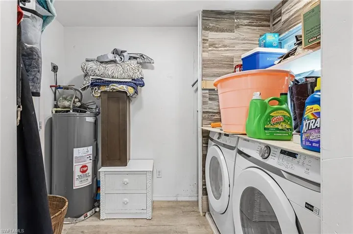 Laundry area with light wood vinyl floors, updated water heater, and washer and dryer