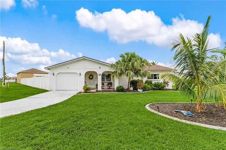View of front of home with an attached garage, a front lawn, driveway, and stucco siding