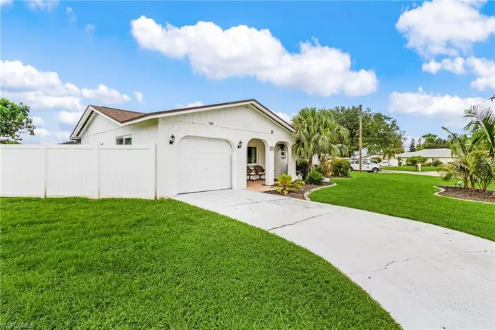 View of property exterior with an attached garage, a lawn, concrete driveway, and stucco siding