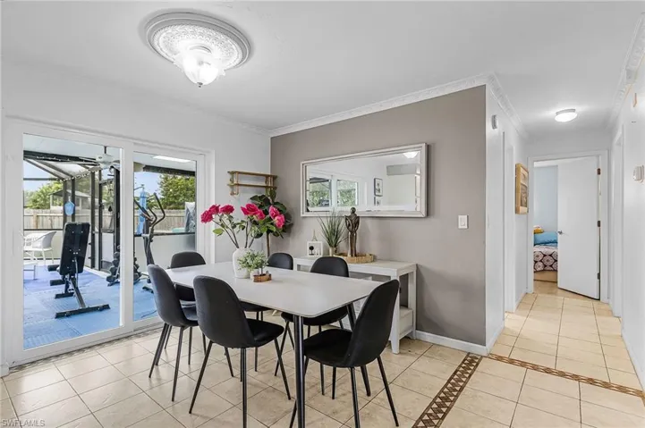 Dining area with light tile patterned floors, ornamental molding, and inlaid floor details