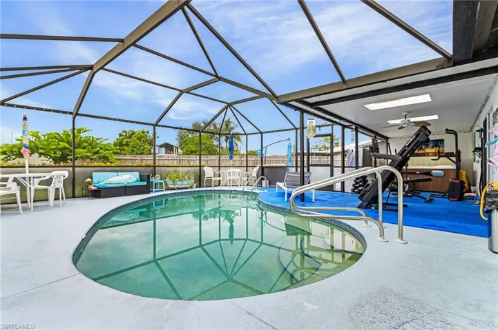 View of pool featuring screened pool enclosure, a fenced backyard,