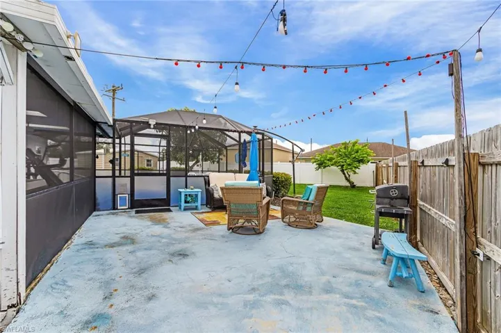 Fenced backyard featuring a large concrete patio for grilling & great for a fire pit area.