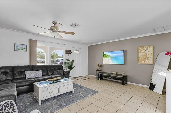 Living room featuring light tile patterned floors and crown molding