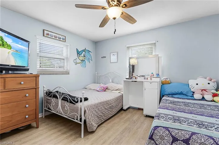 Bedroom with new light wood-style vinyl floors and ceiling fan