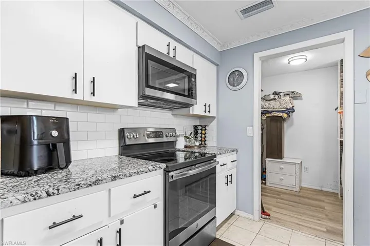 Kitchen with appliances with stainless steel finishes, white cabinets, decorative backsplash, and light tile patterned floors