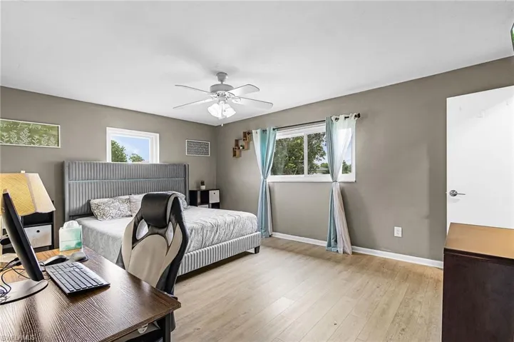 Main Bedroom with new light wood-style vinyl floors, multiple windows, and a ceiling fan