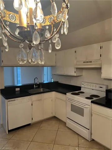 Kitchen featuring white range, white cabinets, dishwasher, and dark countertops
