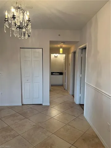 Corridor with a chandelier and light tile patterned flooring