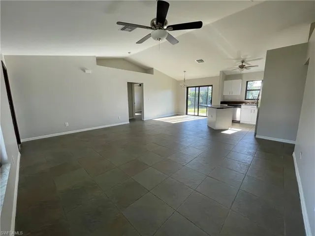 Unfurnished living room featuring a chandelier, vaulted ceiling, and ceiling fan