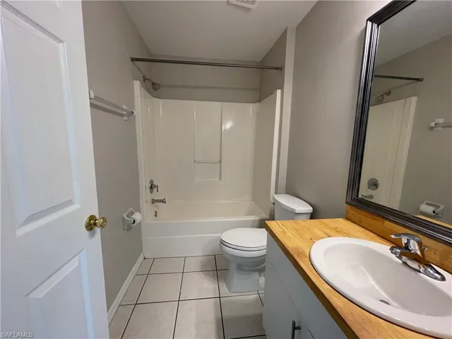 Bathroom featuring shower / bathtub combination, vanity, and light tile patterned flooring