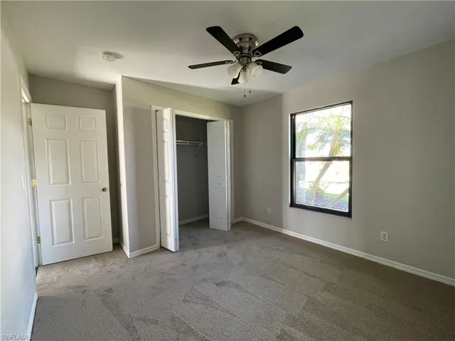 Unfurnished bedroom with carpet, a closet, and a ceiling fan