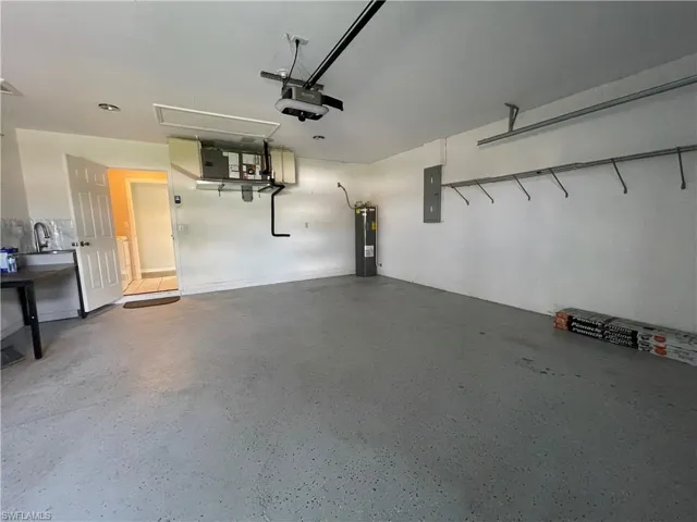 Garage with electric panel, water heater, and a garage door opener